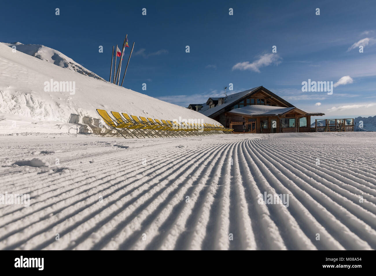 Yellow sun loungers on the slope Dolomites, ski area. Sunny day. Ski area with beautiful slopes. Empty ski slope in winter on a sunny day. Prepared pi Stock Photo