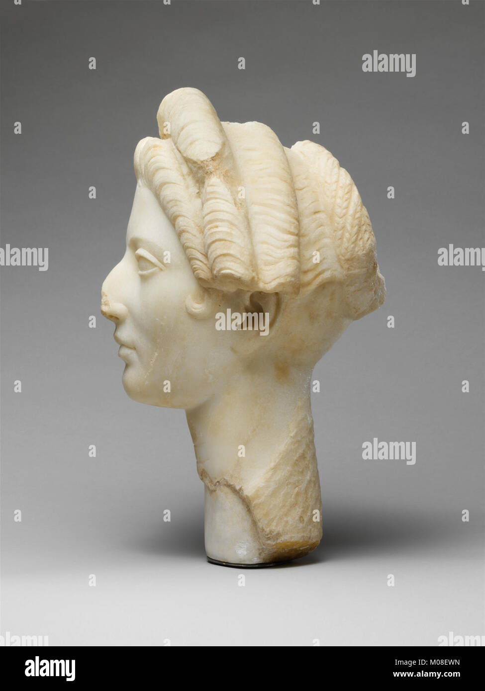This marble portrait of a young woman displays detailed facial features and a classical pose, exemplifying period artistic style and craftsmanship. Stock Photo