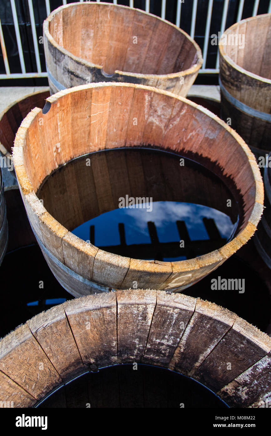 Old half barrels filled with water reflecting the surroundings. Stock Photo