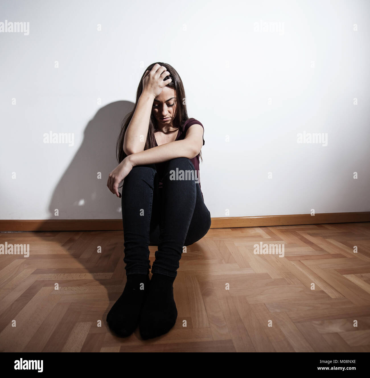 Lonely Depressed young woman sitting on floor in empty dark room ...