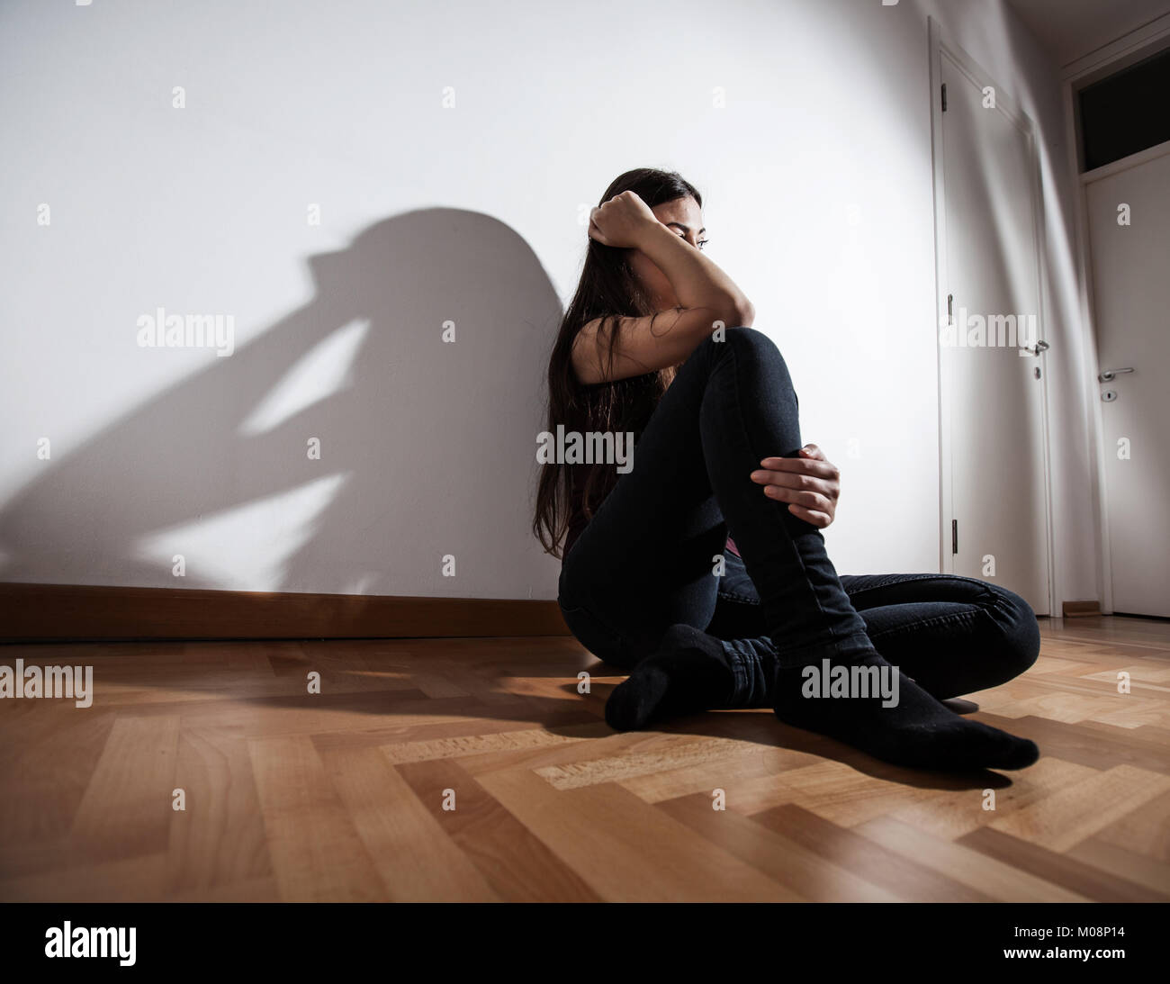 Lonely Depressed young woman sitting on floor in empty dark room ...