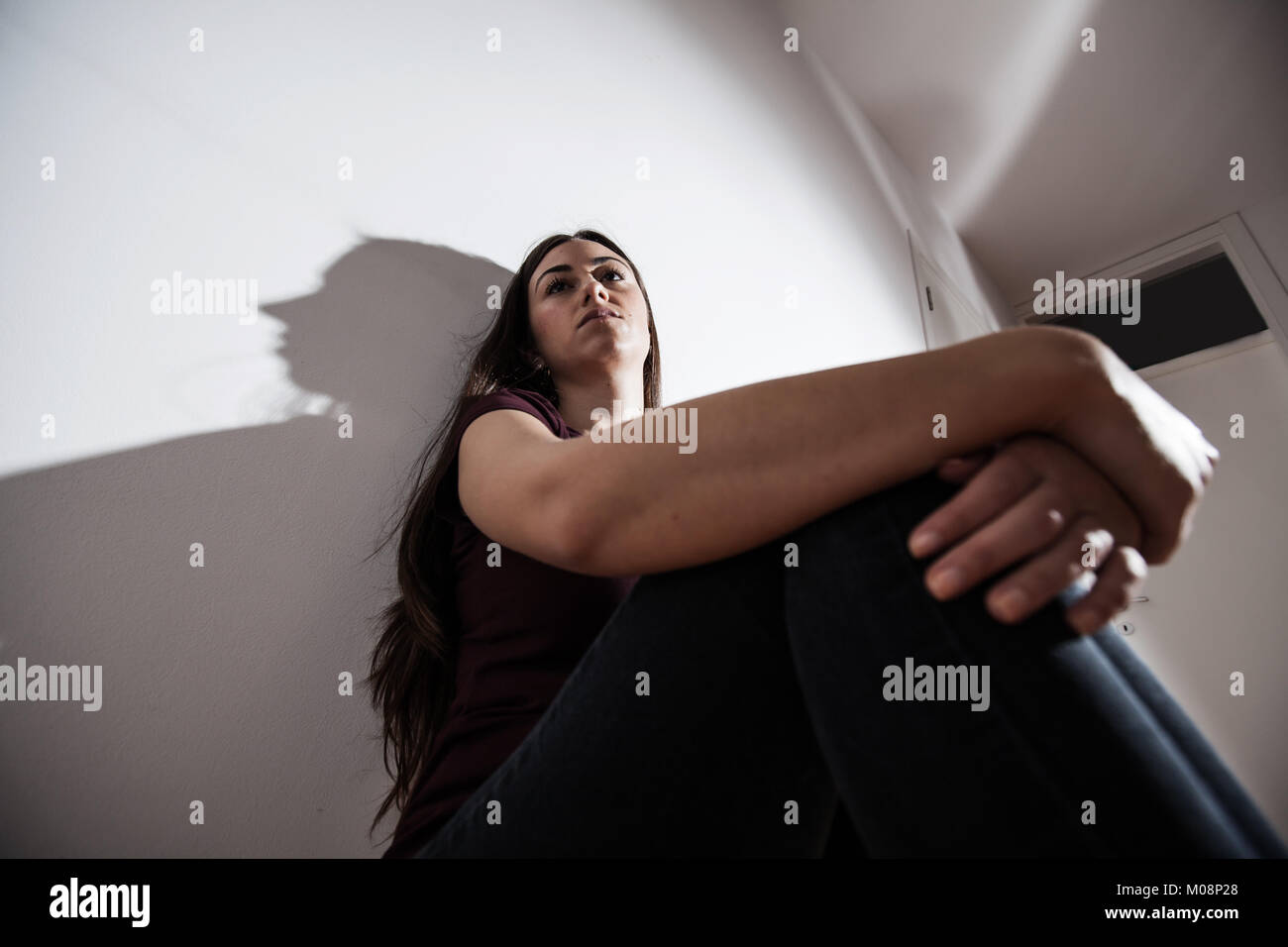 Lonely Depressed young woman sitting on floor in empty dark room ...