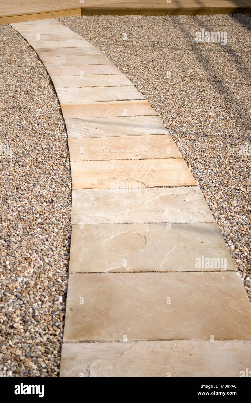 Curving stone slab path through chippings leading to deck Stock Photo