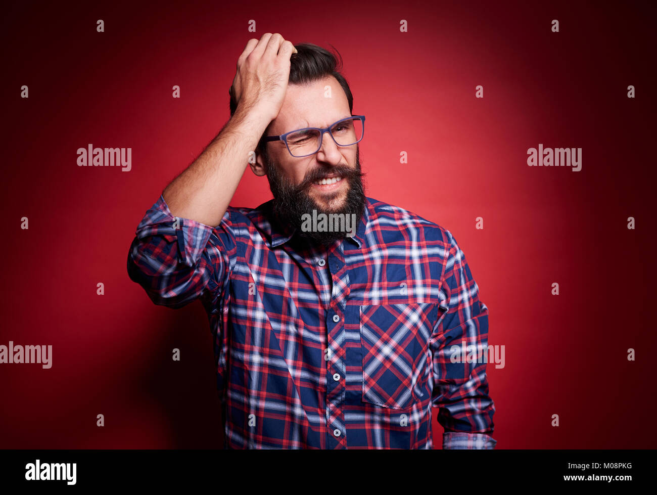 Confused man scratching head st studio shot Stock Photo