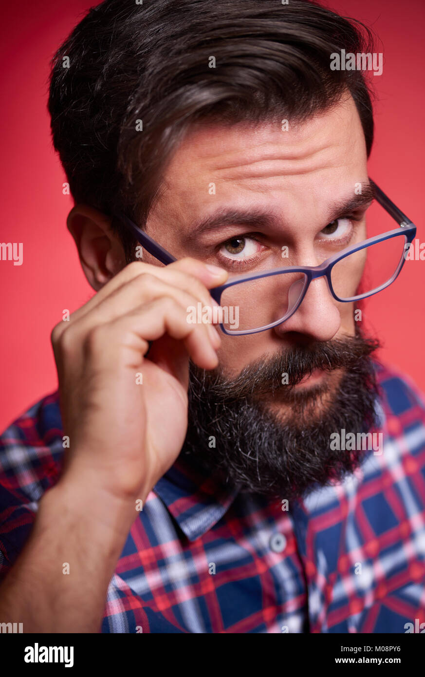 Displeased and suspicious man adjusting his eyeglasses Stock Photo - Alamy