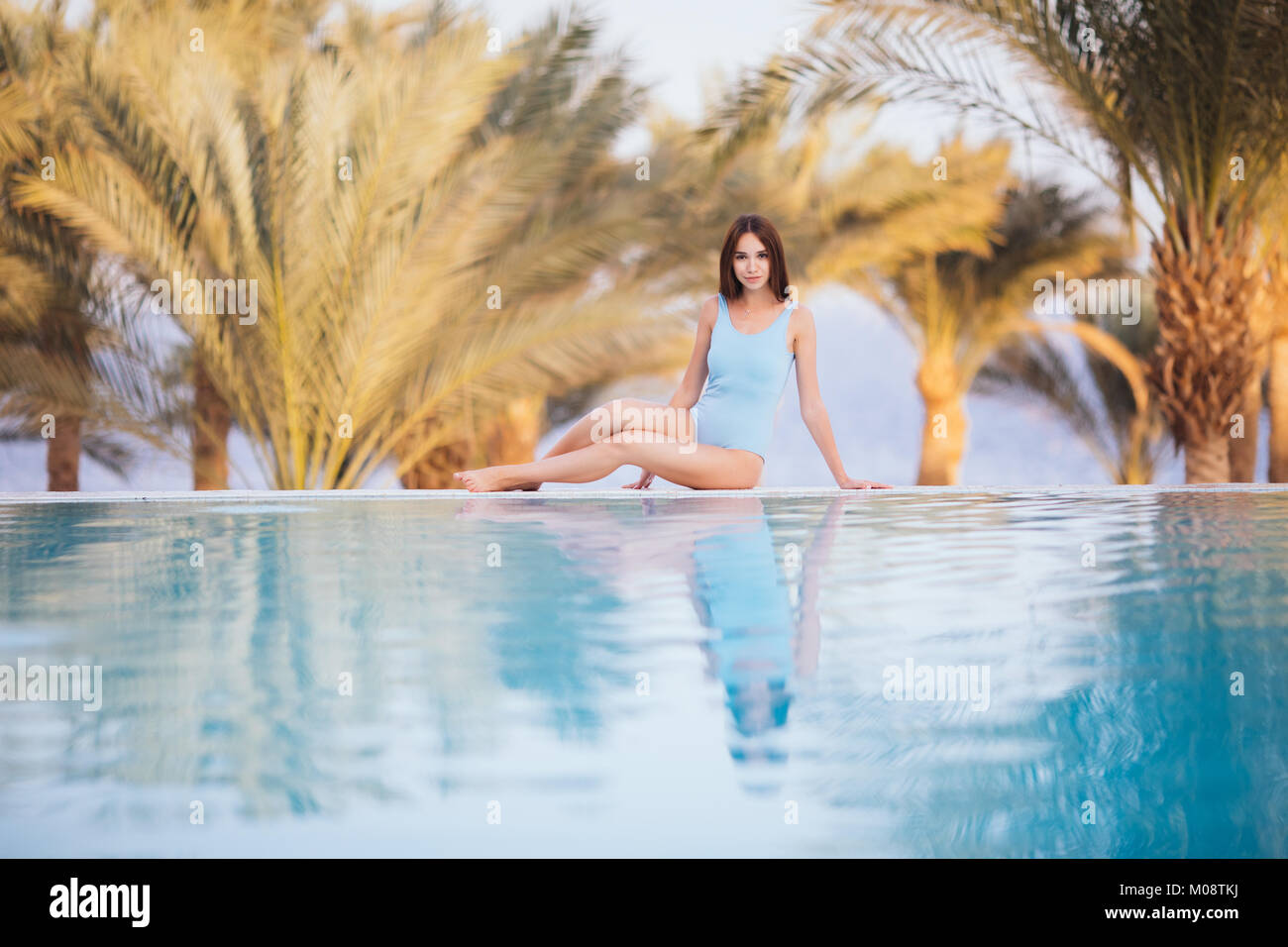 woman sitting on the edge of infinity pool with stunning view Stock ...