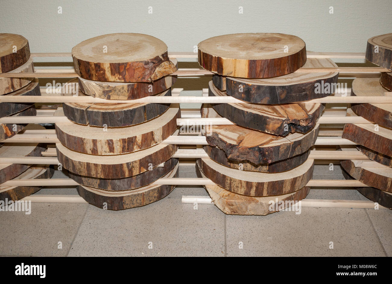 Folded stack of transverse wooden saw cuts stands vertically on floor. Stock Photo