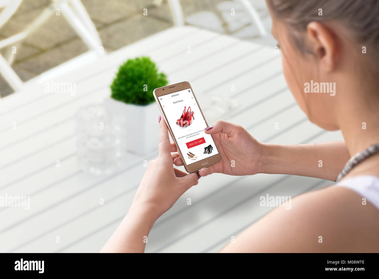 Woman shopping online with smart phone. Search for woman shoes. Coffee shop table in background. Stock Photo