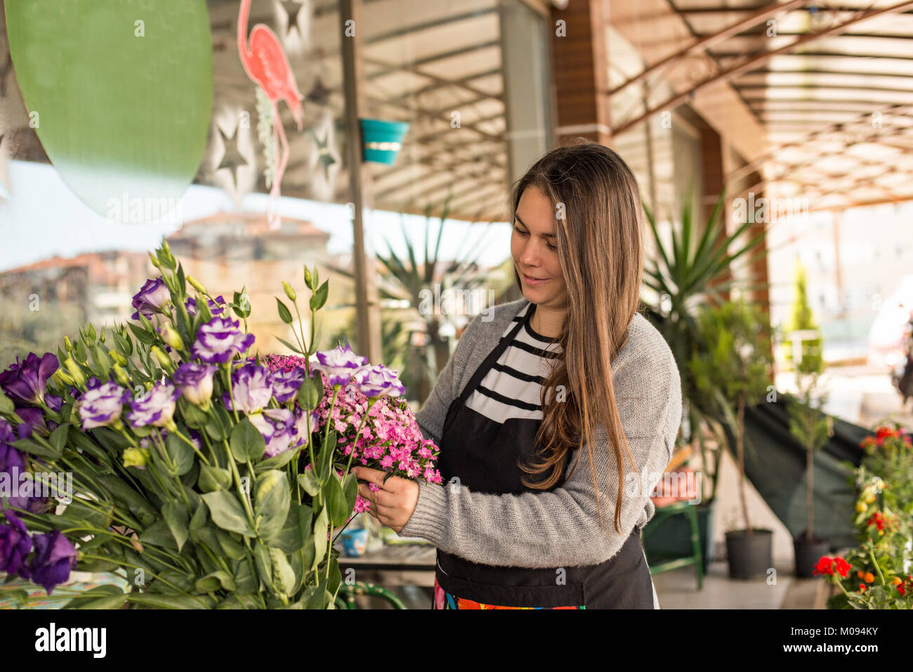 Small business concept. Smilng female florist picking flowers in a flower shop. Horizontal composition Stock Photo