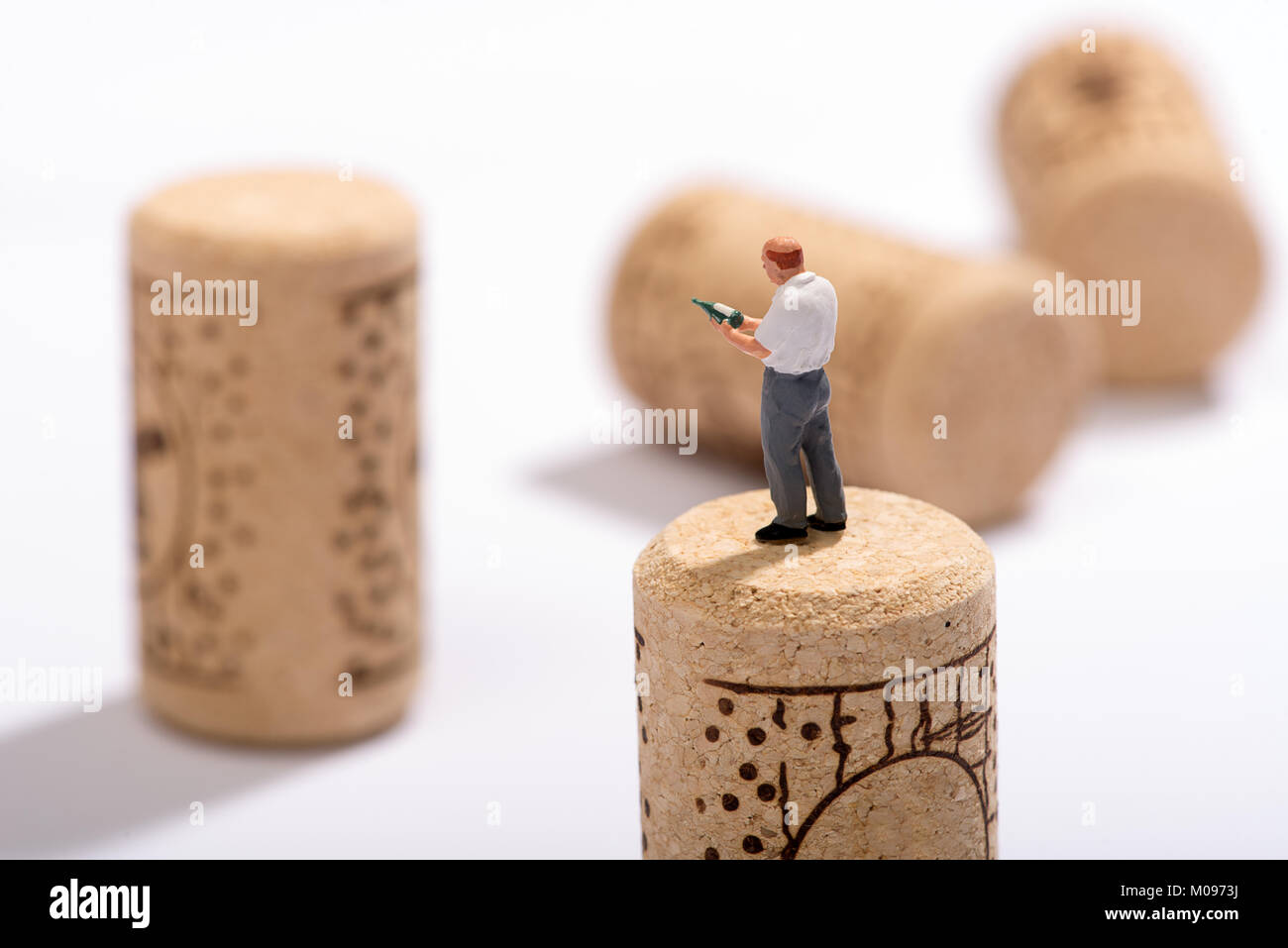 Miniature figure of a sommelier or wine expert standing on a cork looking at a bottle in his hand for pairings at a restaurant Stock Photo