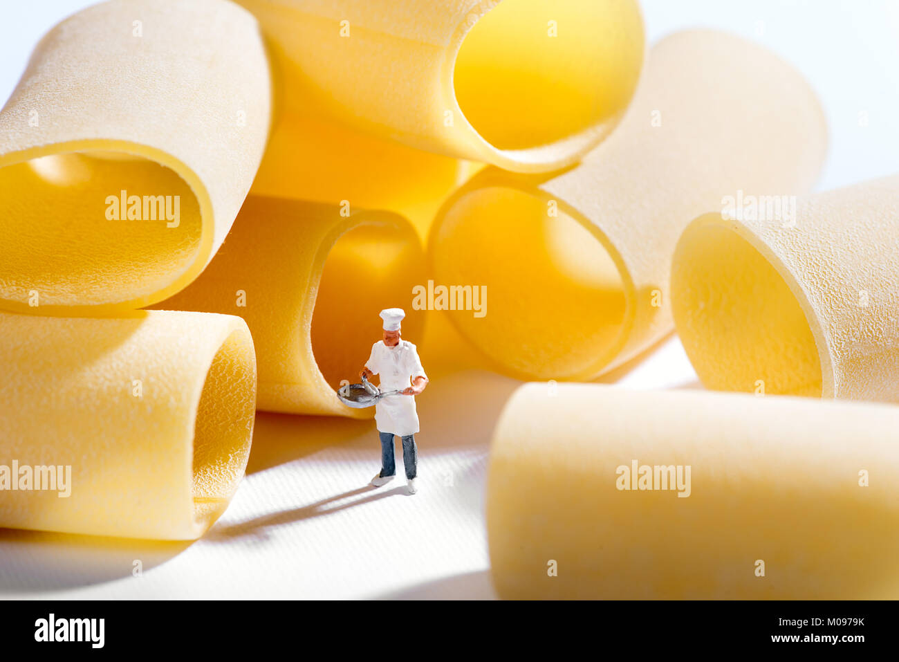 Miniature figure of a chef standing amongst dried Italian pasta tubes in a concept of cooking and food ingredients Stock Photo