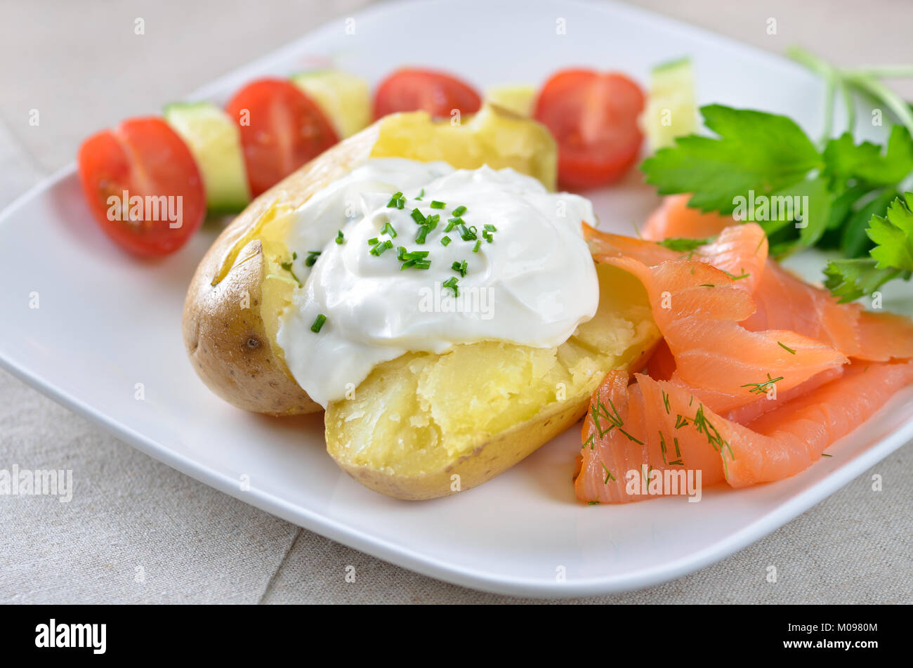 Jacket potato with sour cream, herbs and smoked salmon, tomatoes and