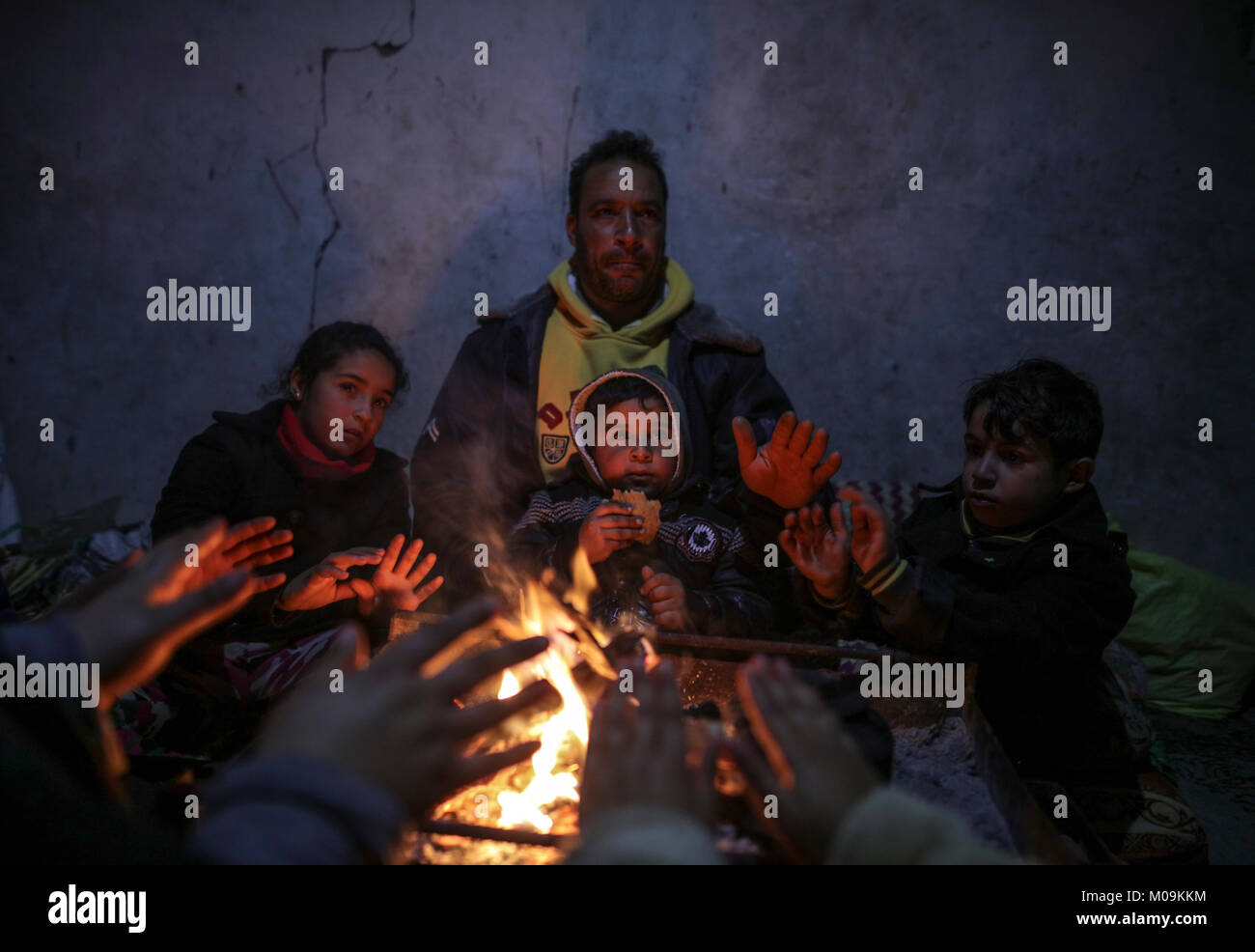 A Palestinian family gather around fire to stay warm amid a stormy ...