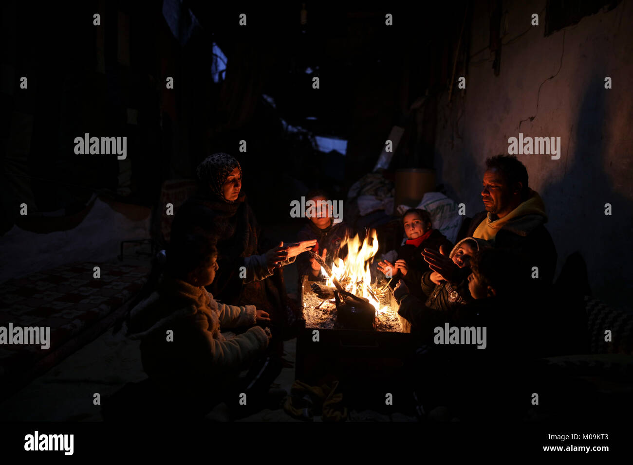 A Palestinian family gather around fire to stay warm amid a stormy ...