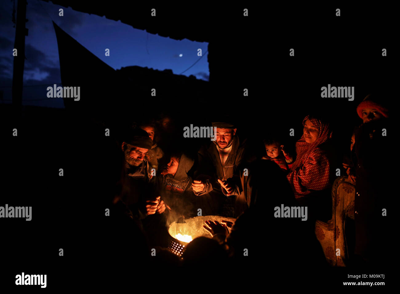 A Palestinian family gather around fire outside their house, to stay ...