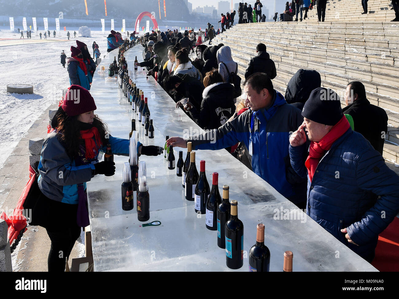 Tonghua, China's Jilin Province. 20th Jan, 2018. Citizens taste wine in front of an ice bar table at the bank of Hunjiang river in Tonghua, northeast China's Jilin Province, Jan. 20, 2018. A 2221.7-square-meter snow picture and a 100.6-meter-long ice bar table were seen recently in the city. Credit: Xu Chang/Xinhua/Alamy Live News Stock Photo