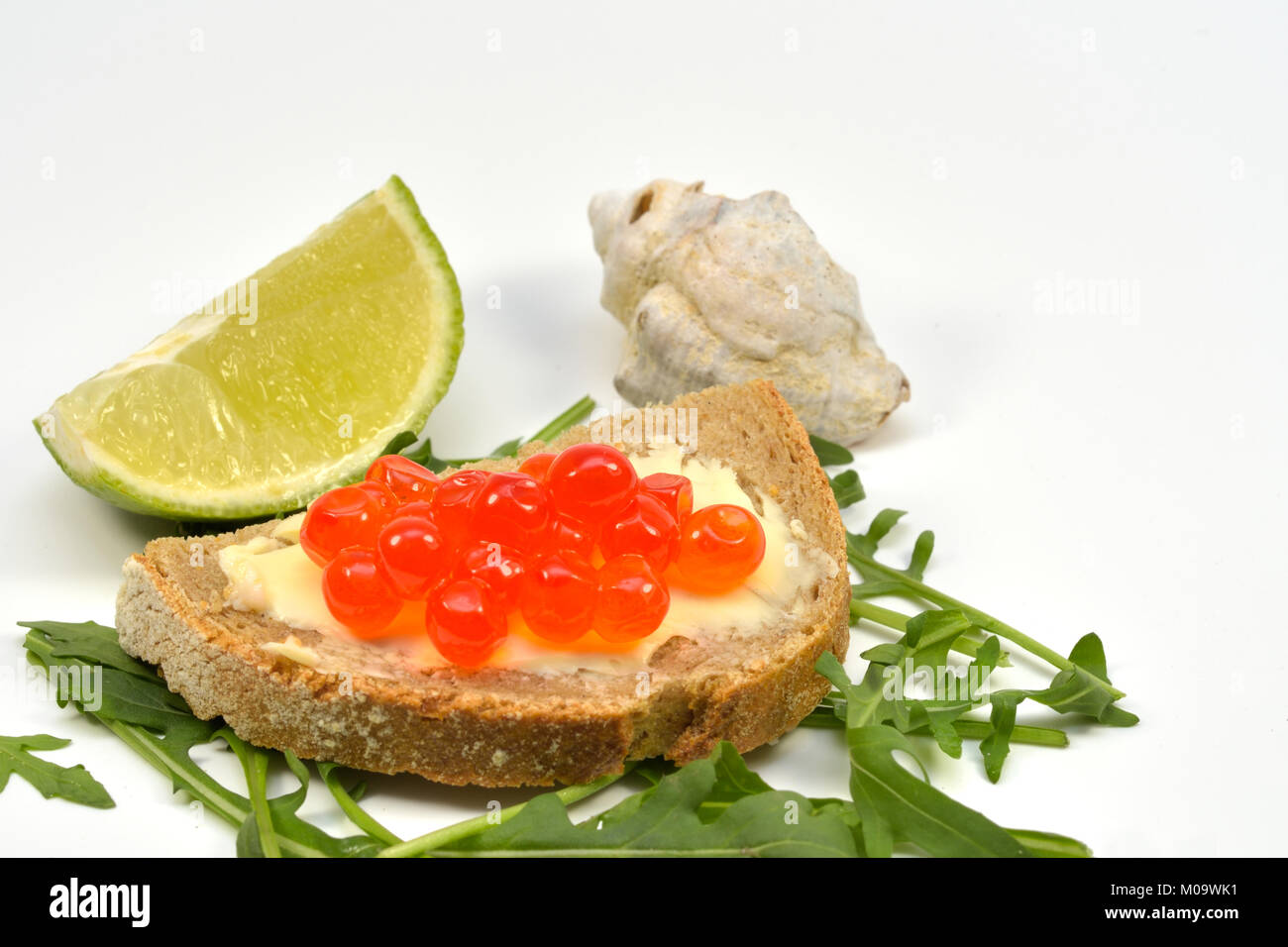 Fresh Salmon Raw Roe Sandwich (Red Caviar) on Rucola Leaves and Slice of Lime, isolated on white background Stock Photo