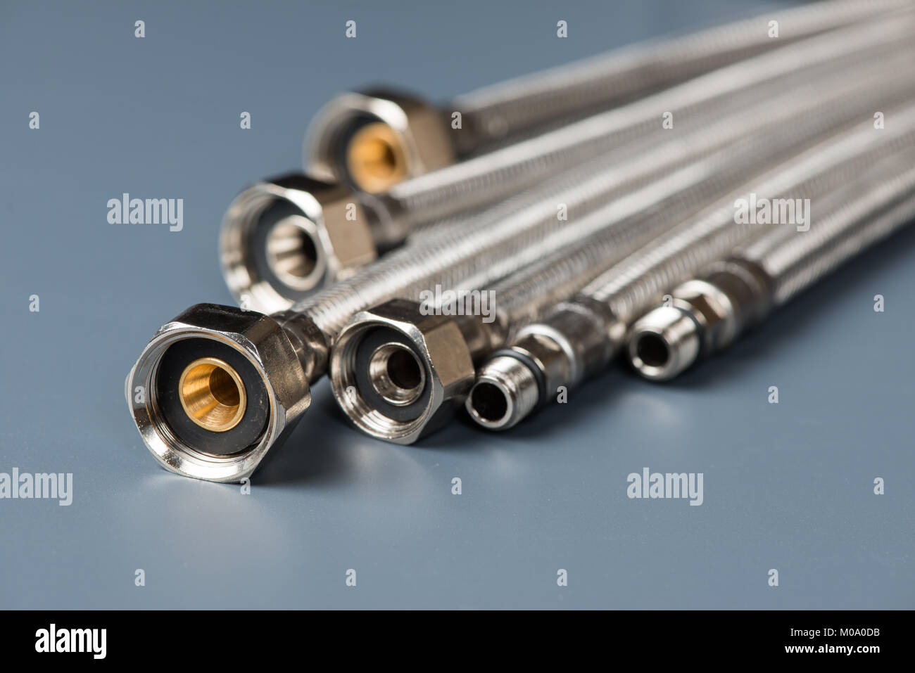 Flexible braided stainless steel water hoses on gray background Stock Photo