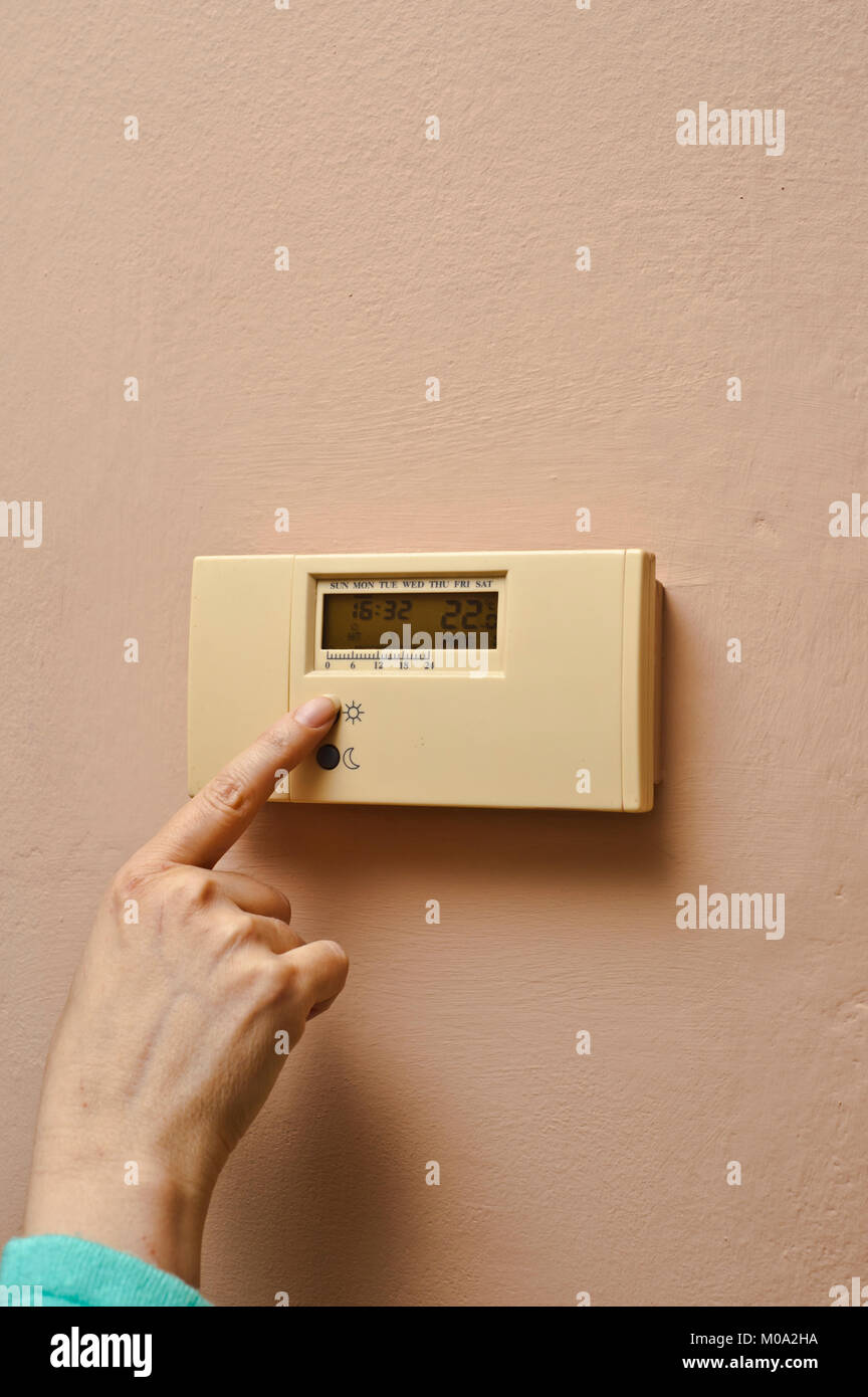 woman hand regulating an home thermostat Stock Photo