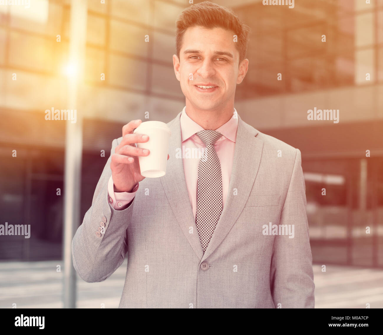Portrait of young successful businessman drinking coffee near large ...