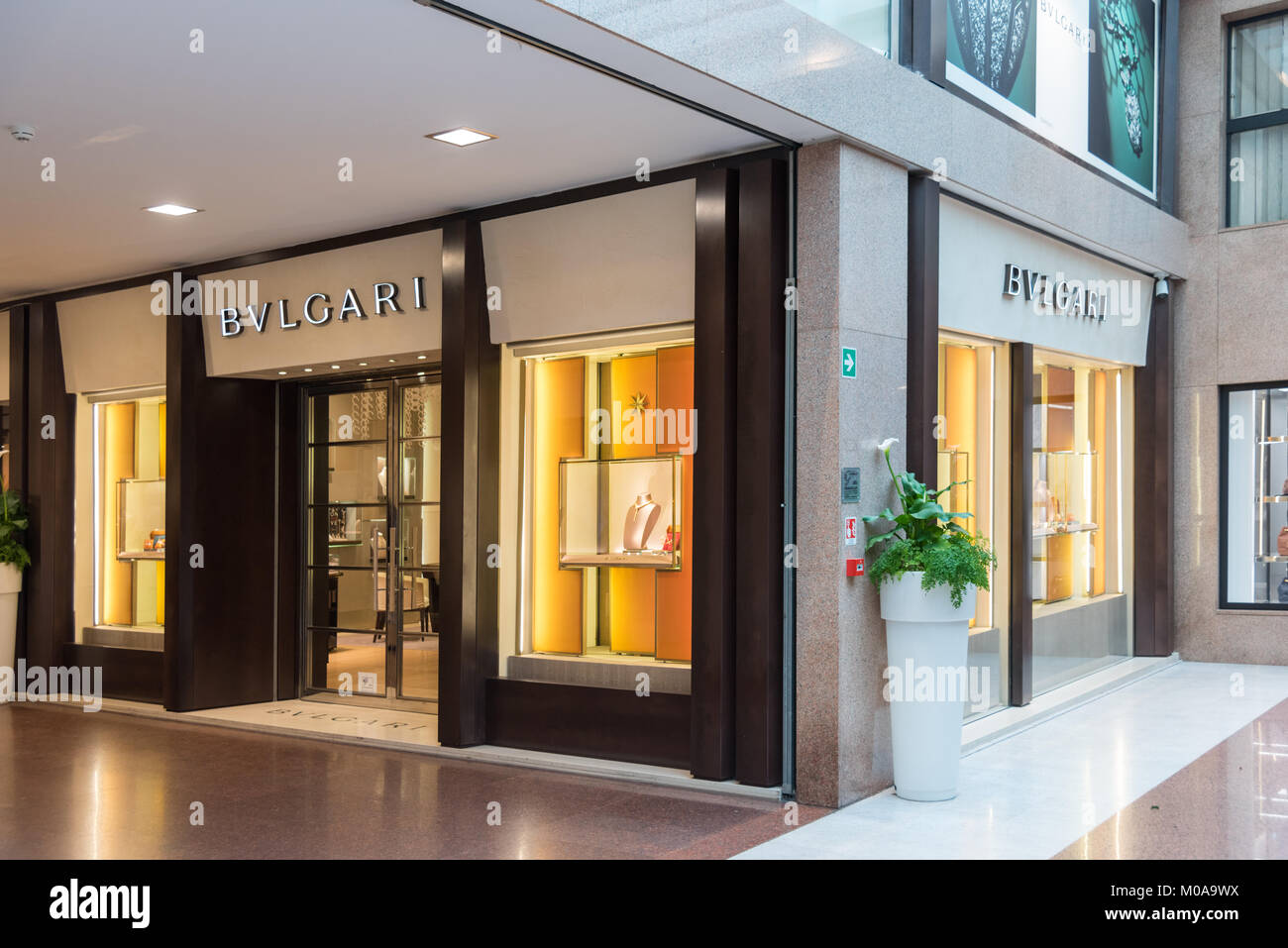 The  Bvlgari or Bulgari jewelery shop in glossy, glass-roofed shopping center full of upmarket designer fashion stores. Stock Photo