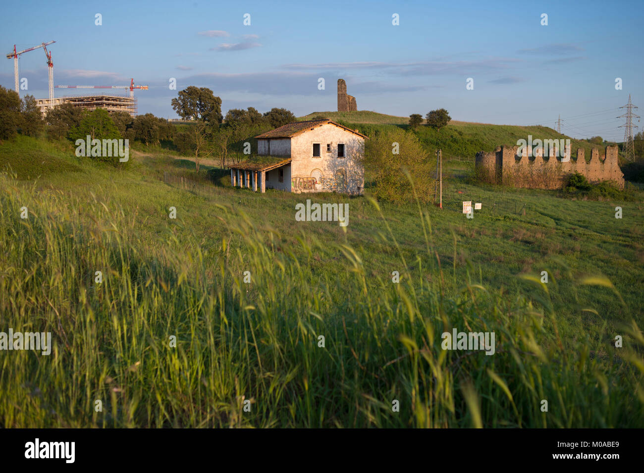 Rome, Italy. Old abandoned country house, ancient medieval ruins and heavy construction in the background, South outskirts of town. Stock Photo