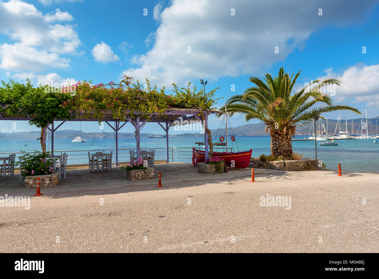 Restaurant tables in Adamas port and palm tree with beautiful view of ...