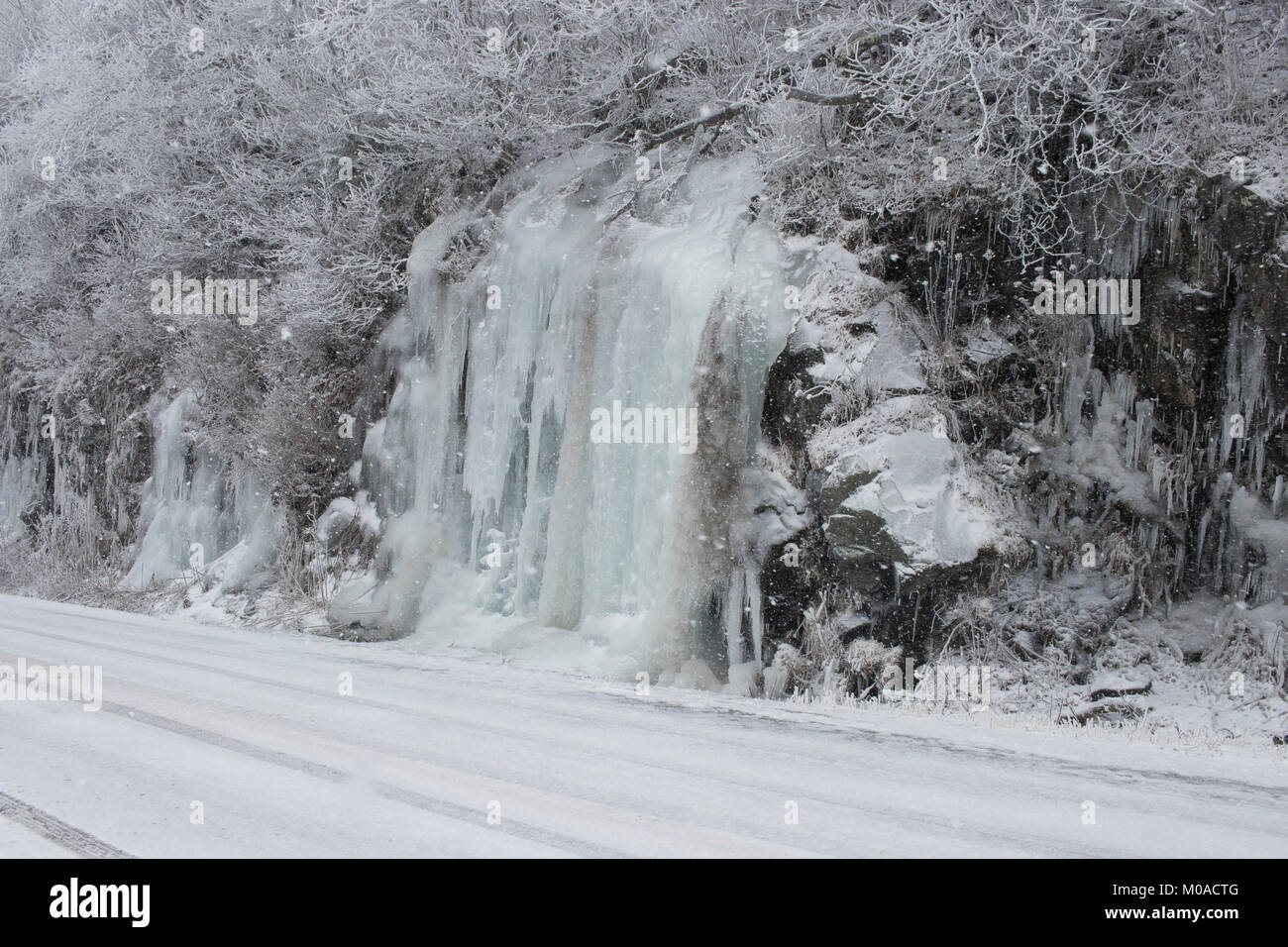 winter image of a frozen ice wall or cliff with ice sickles. Stock Photo