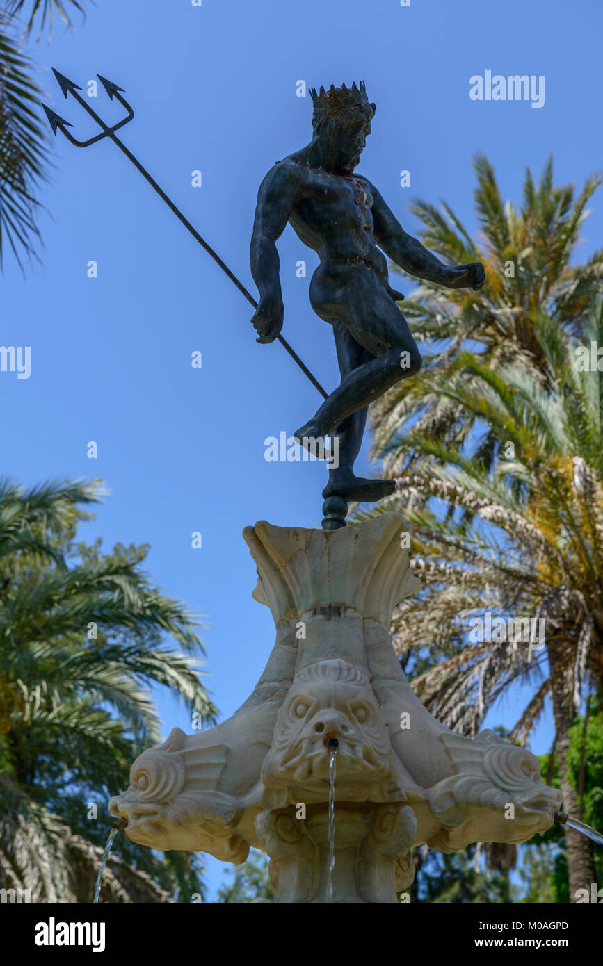The Alcazar of Seville, Spain. A statue of Neptune on the crown of a fountain in the gardens . Stock Photo