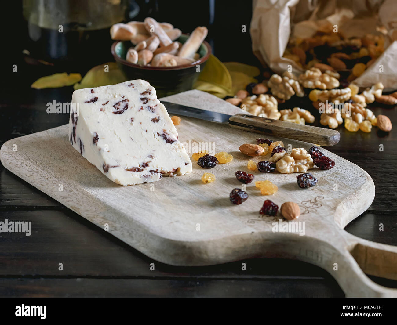 Creamery cheese with cranberries, nuts and raisins on wooden cutting board. Stock Photo