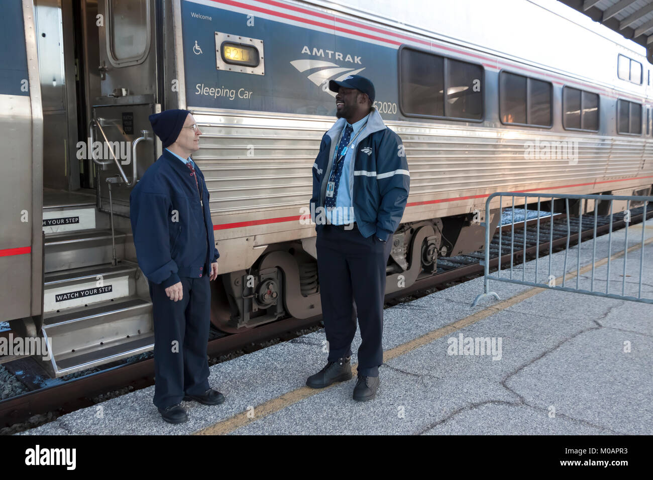 Two male Amtrak porter employees having a conversation while at a station break in Florida. Stock Photo