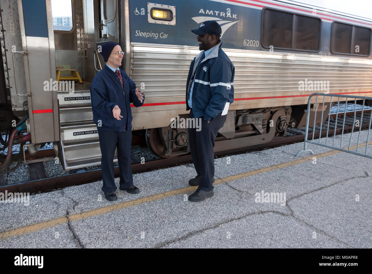 Two male Amtrak porter employees having a conversation while at a station break in Florida. Stock Photo