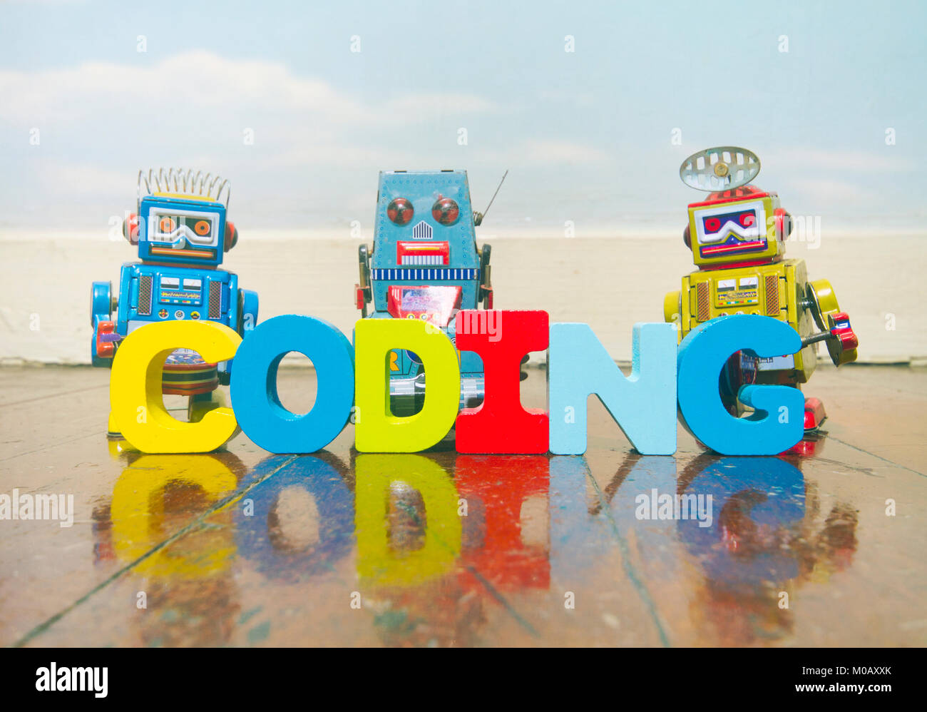 the word coding wit wooden letters on a old wooden floor with retro robot toys Stock Photo
