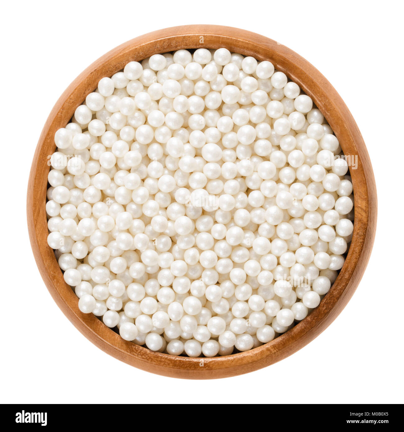 White nonpareils in wooden bowl. Hundreds and thousands. Decorative confectionery of tiny balls, made with sugar and starch, used for decoration. Stock Photo