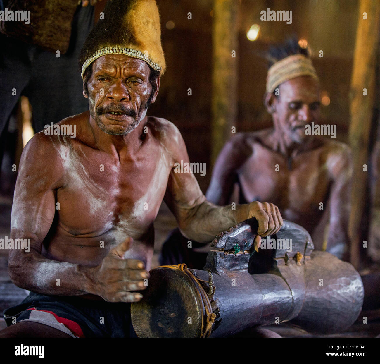 Portrait of a man from the tribe of Asmat people with a drum in the men`s house. Asmat Welcoming ceremony. Stock Photo
