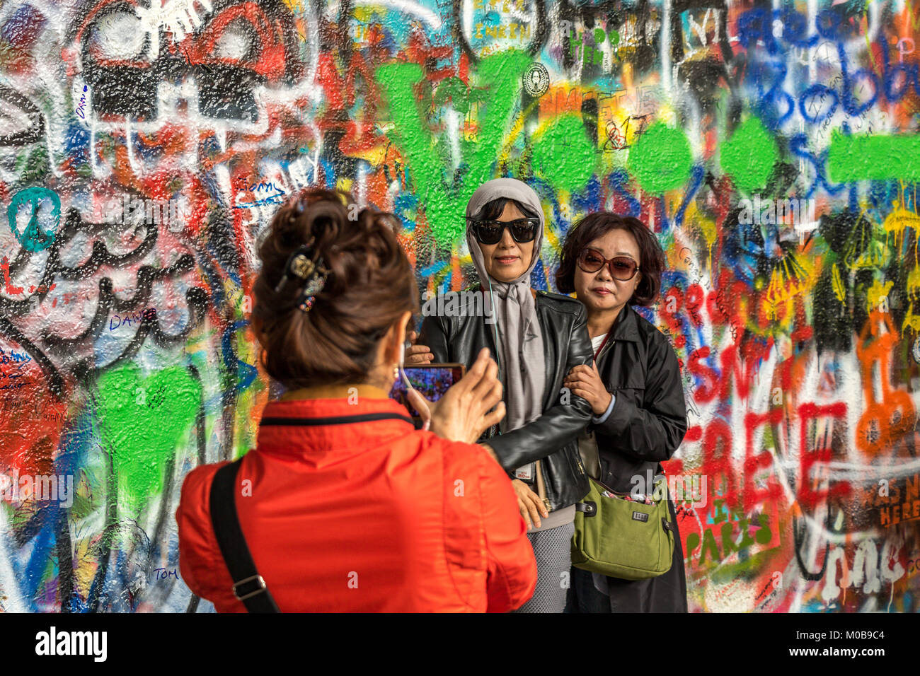 Chinese tourists posing for photographs in front of the Graffiti covered  John Lennon Wall in Prague ,Czech Republic Stock Photo