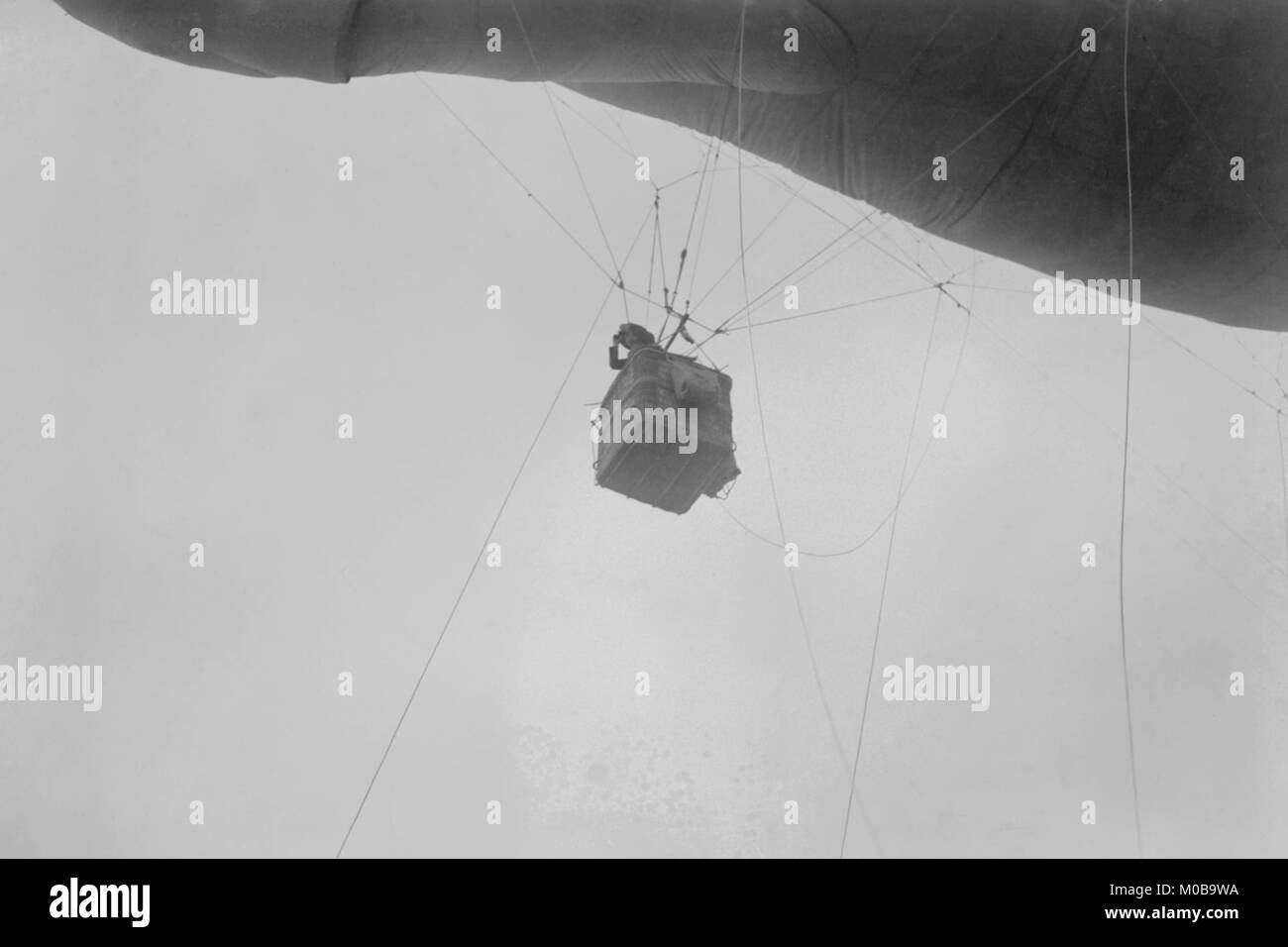 Military Observer hangs from a Balloon by guide wires looking over battlefield Stock Photo