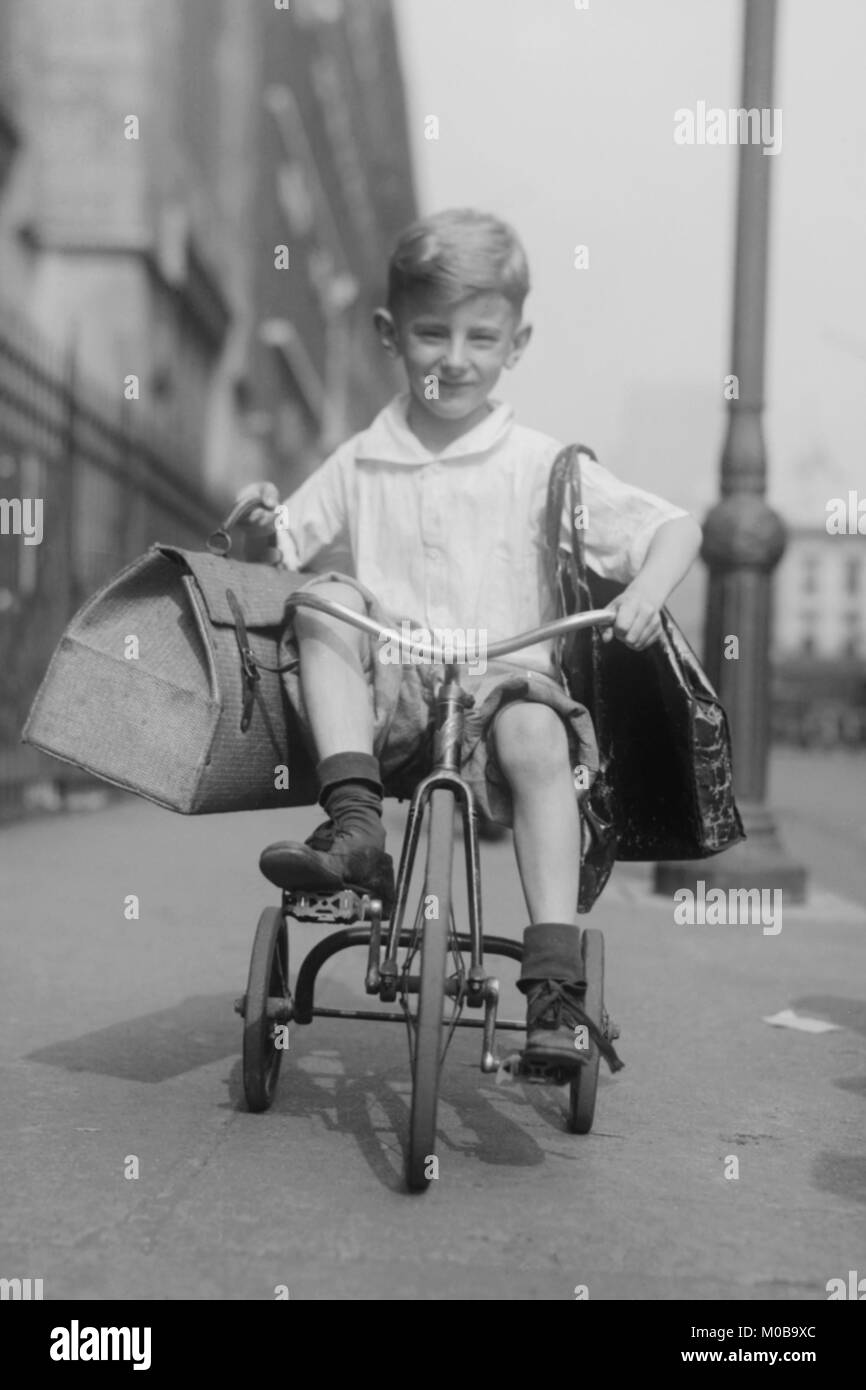 Toddler on Tricycle Carries small satchels after making a food sale Stock Photo
