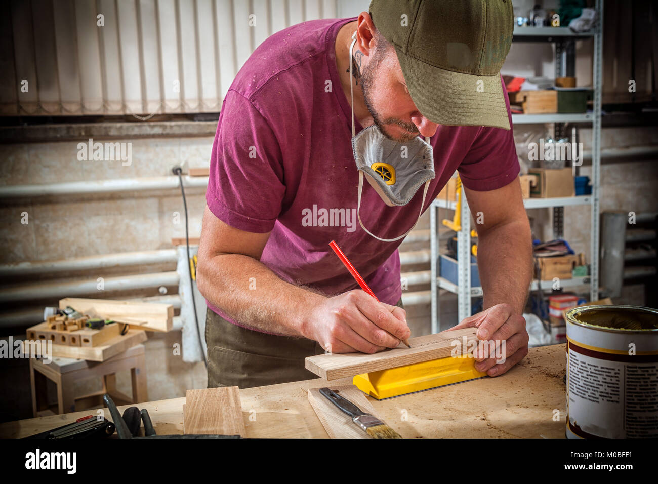 A young strong man builder carpenter works with a wooden bar for making