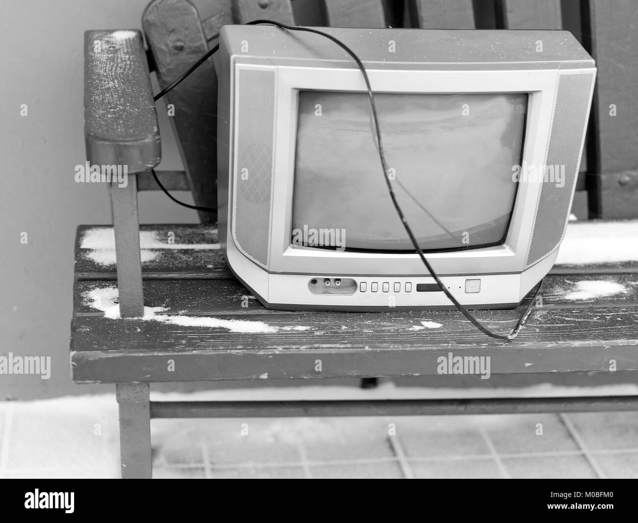 Old tv set on the bench, seems abanoned. In black and white Stock Photo
