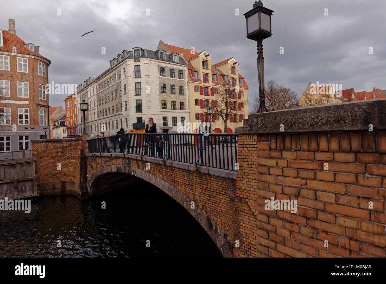 Copenhagen, Denmark - November 07, 2016: People walking on Snorrebro bridge across Chrisianshavn canal. The canal is noted for its bustling sailing co Stock Photo