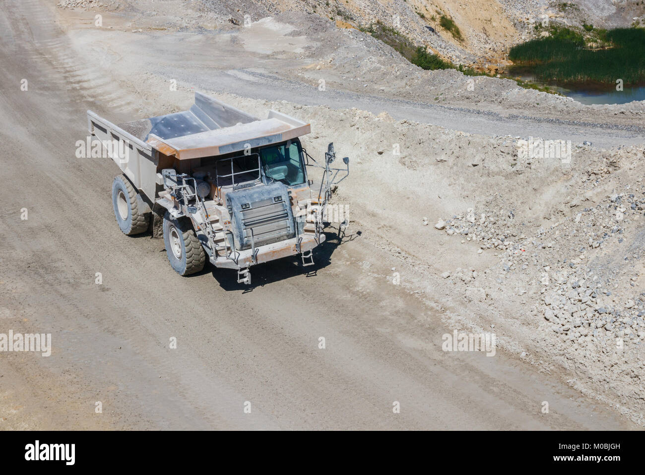 Huge dump truck driving along a dirt road at the ENCI (First Dutch Cement Industry) marl quarry at the Mount Saint Peter. Maastricht, The Netherlands. Stock Photo