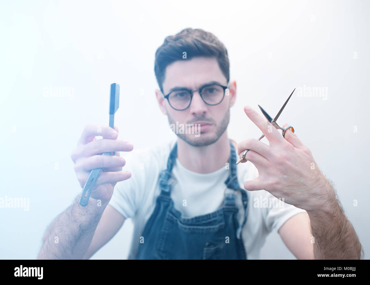 Barber keeps scissors and a razor against the background of a white