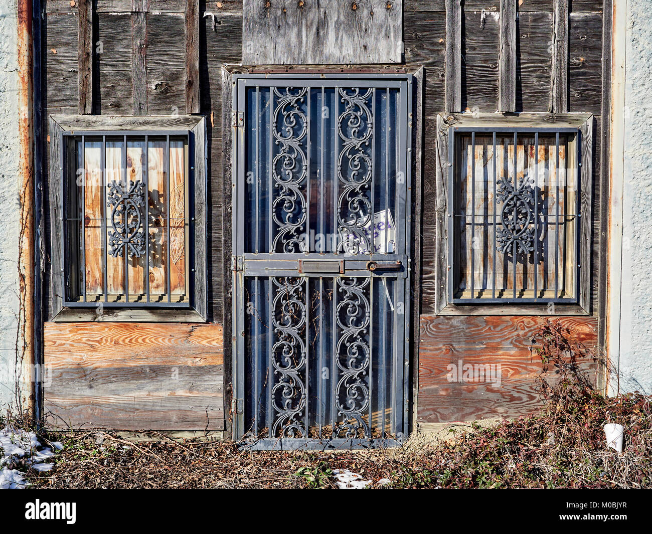 Exterior of dirty, weathered old abandoned wooden building with bars on the doors and windows in the industrial section of Montgomery Alabama, USA. Stock Photo