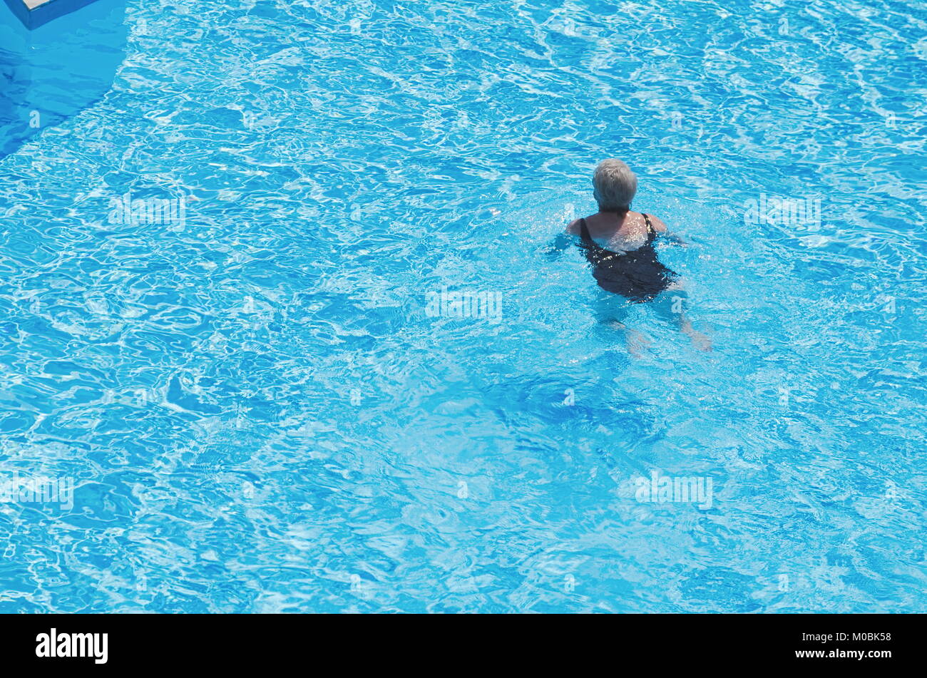 Old Woman in Blue Swimming Pool on a Summer Day Stock Photo