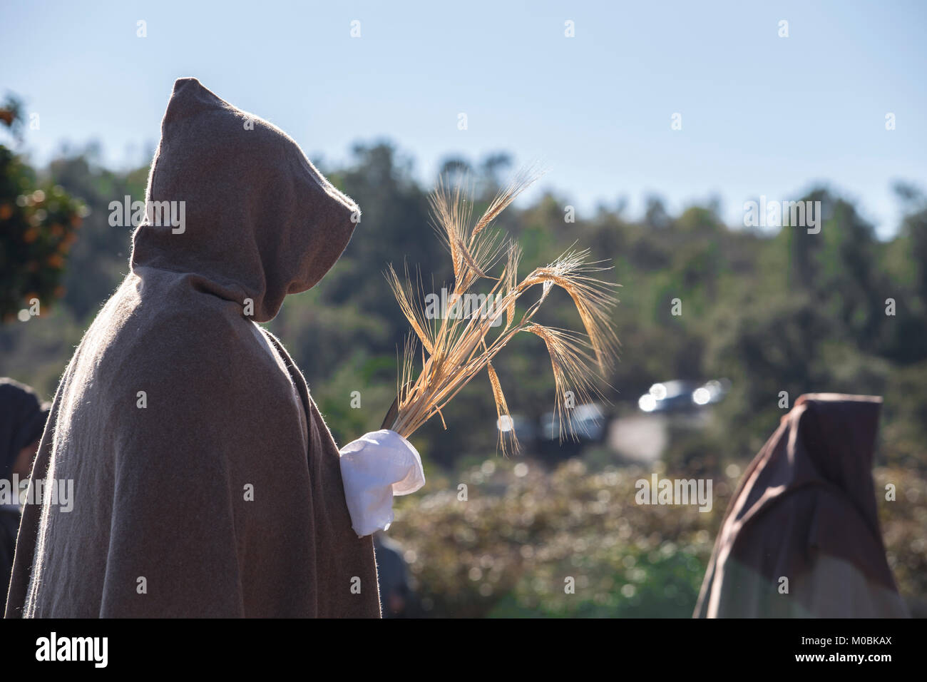Hooded entourage members with wheat bundle offering. Reenactment of Iberian Goddess Ataecina ritual Stock Photo