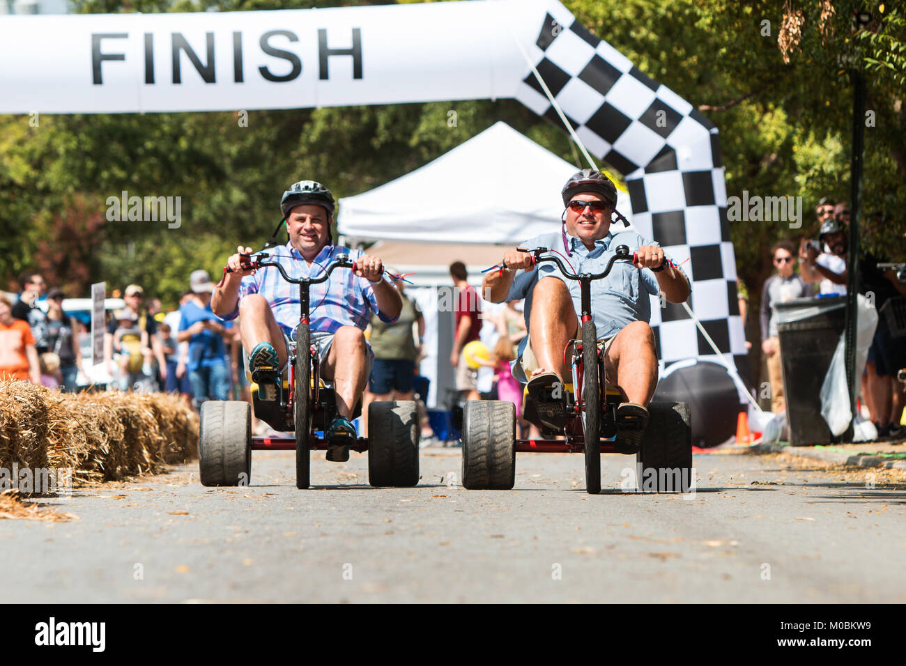 Atlanta, GA, USA - September 23, 2017: Two men race each other on adult big wheels in a friendly competition at the East Atlanta Strut festival. Stock Photo