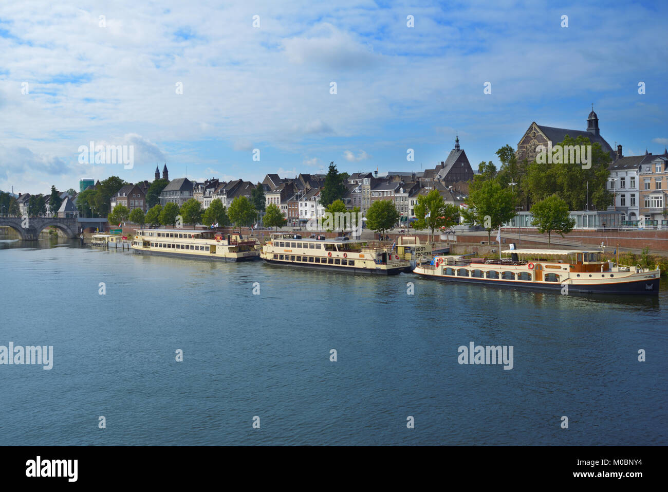 Maastricht, Netherlands - September 8, 2013: Trip boats wait for visitors on the Meuse river near the Roman bridge. Maastricht is considered as the ol Stock Photo
