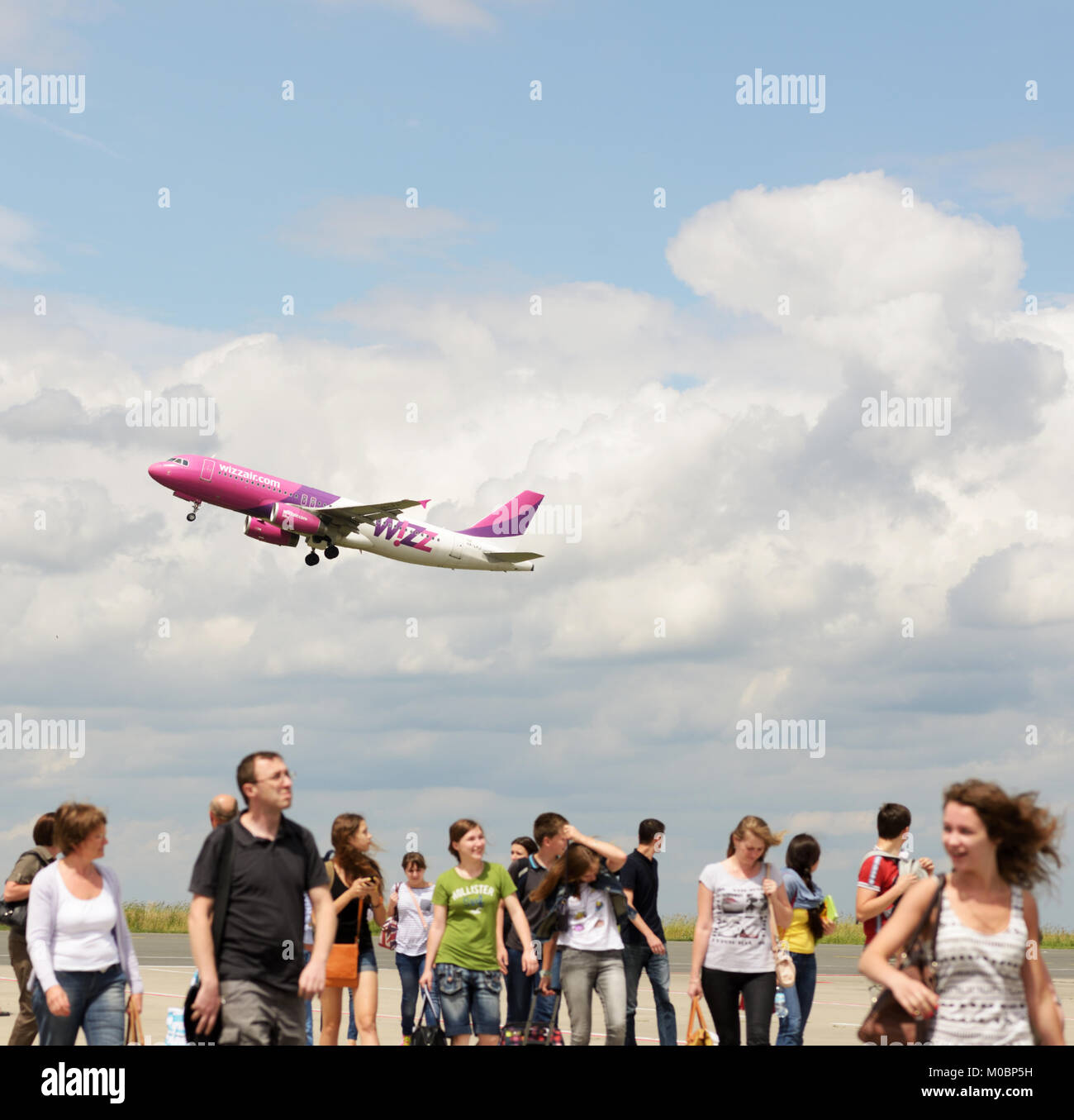 Dortmund, Germany - June 22, 2013: Passengers on a runway in the airport of Dortmund, Germany on June 22, 2013 under Wizzair plane taking off. Created Stock Photo