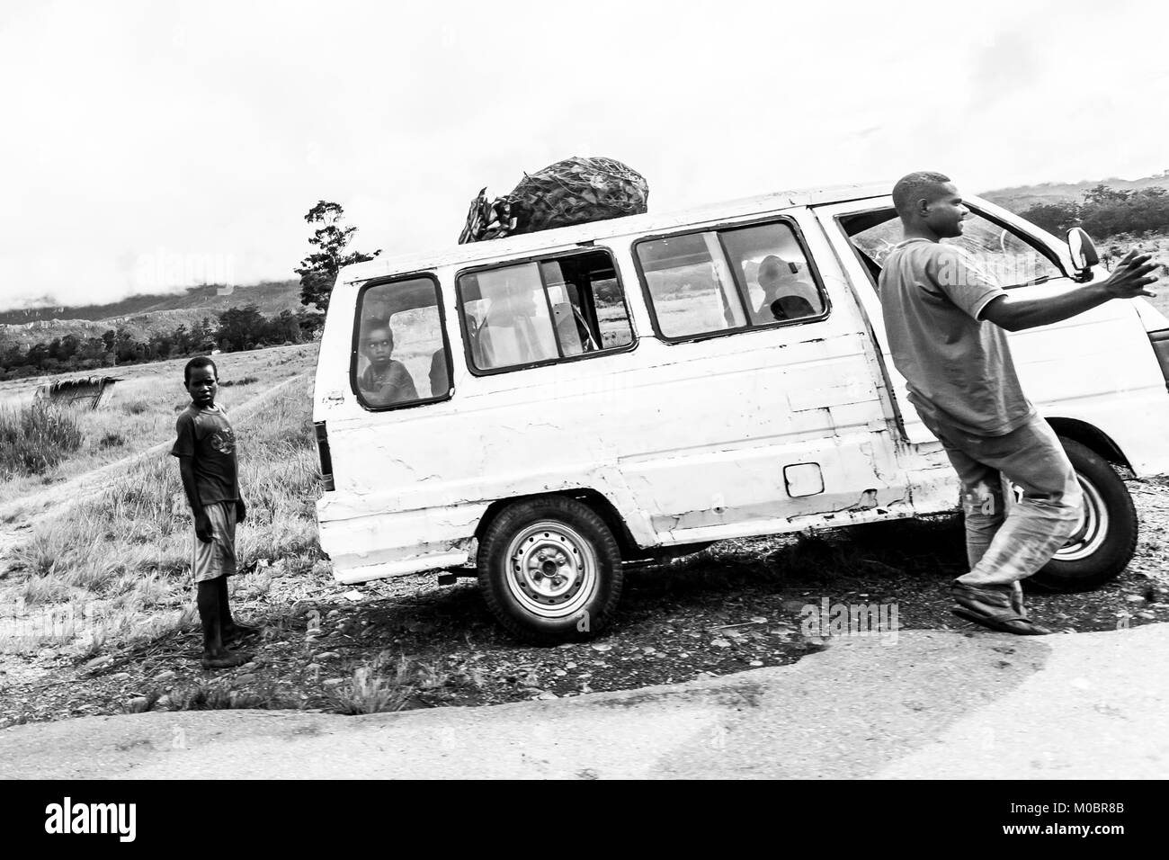 Local Dani people ride the minibus in Baliem Valley, Indonesia. These minibuses hold about 30 people and their luggage. Wamena. Indonesia. Stock Photo